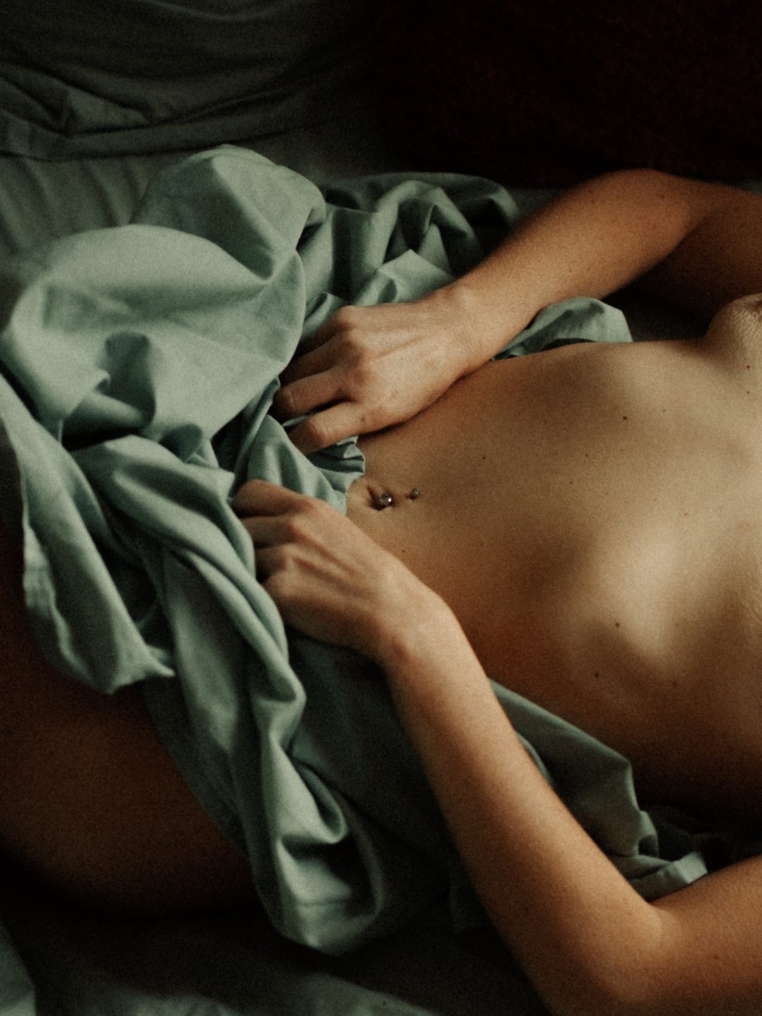 Nu artistique, cadrage serré sur une main et un drap, lumière douce