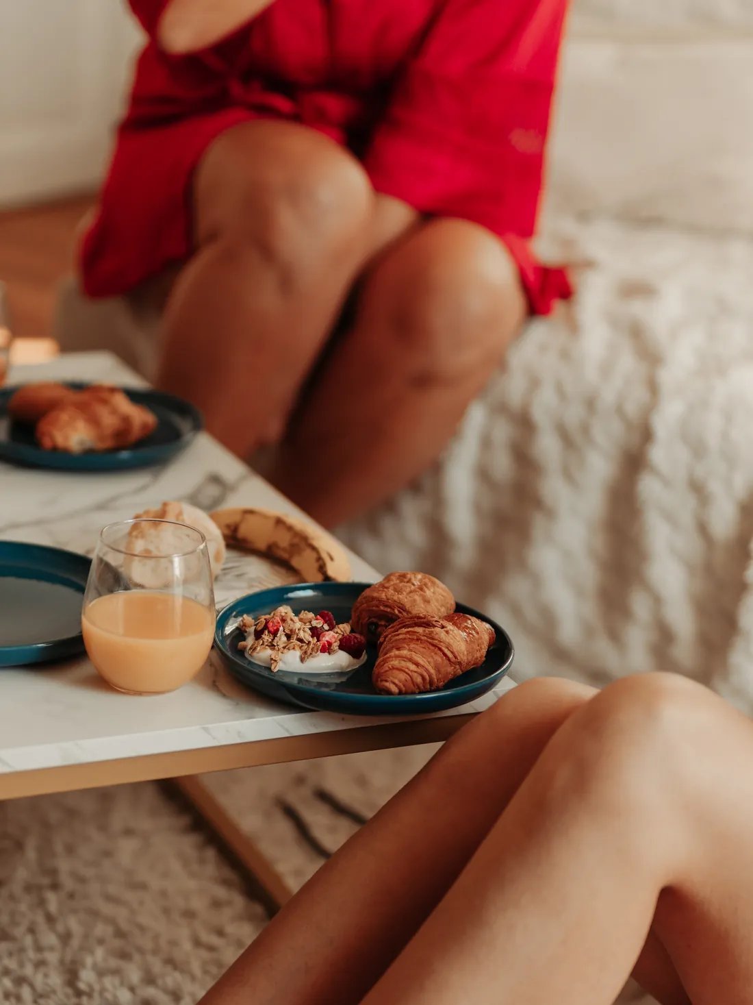 Croissants, jus d'orange et bol de fruits sur la table basse