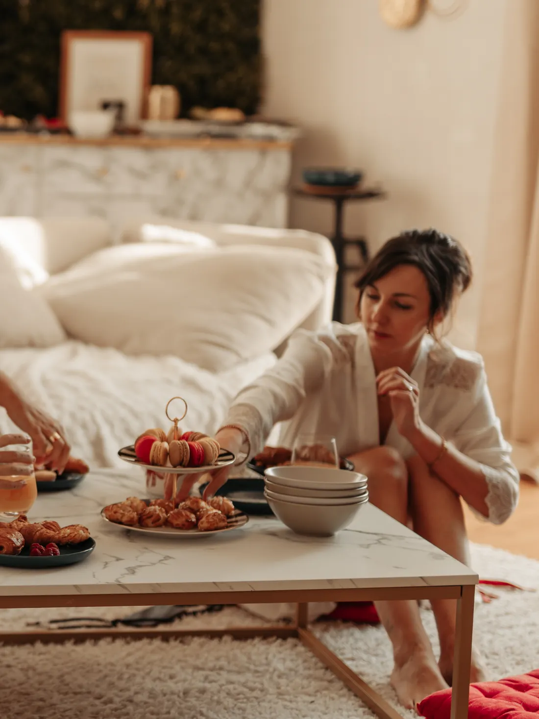 Une copine en peignoir prend un macaron sur la table basse